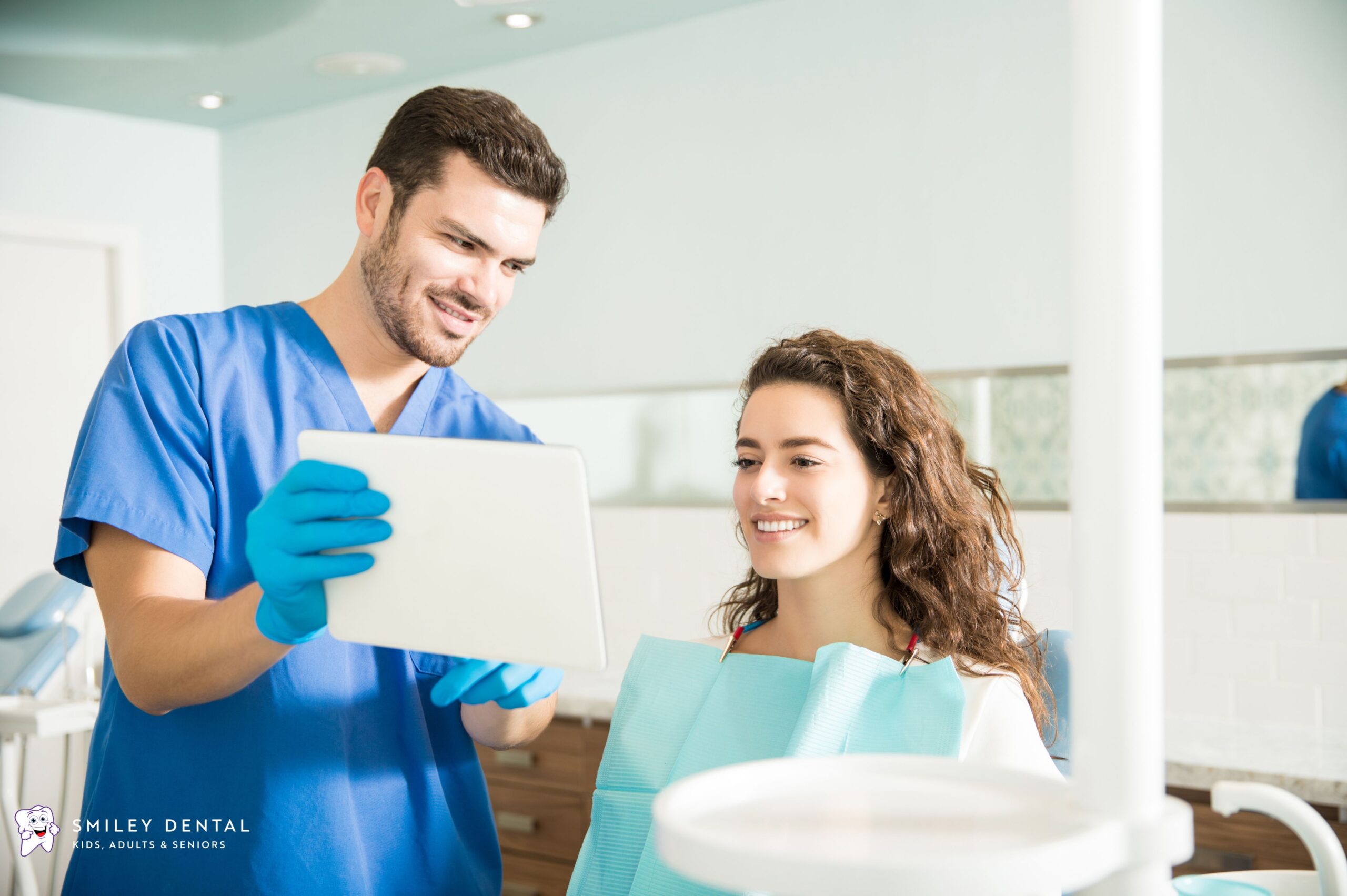 Dentist showing a female patient her treatment plan on a tablet during a dental consultation