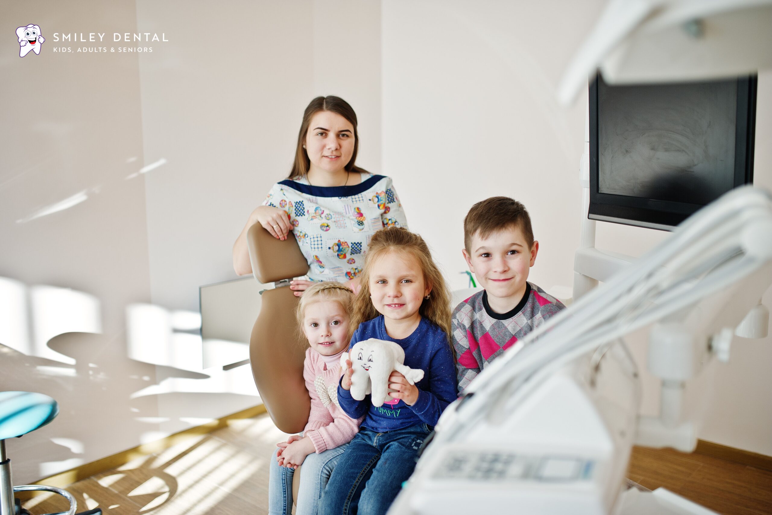Mother and three children sitting together at a family dental office in Roslindale