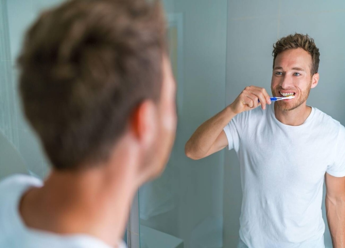 Person brushing teeth but still experiencing bad breath due to gum disease or dry mouth