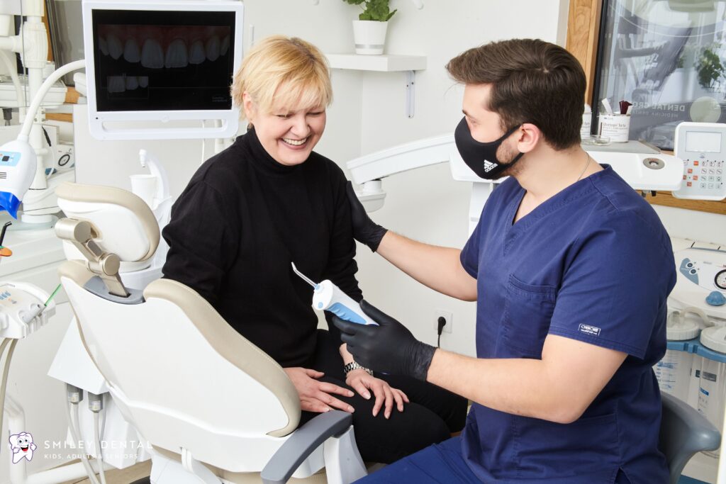 Smiling patient consulting with a cosmetic dentist over digital tooth imaging on screen