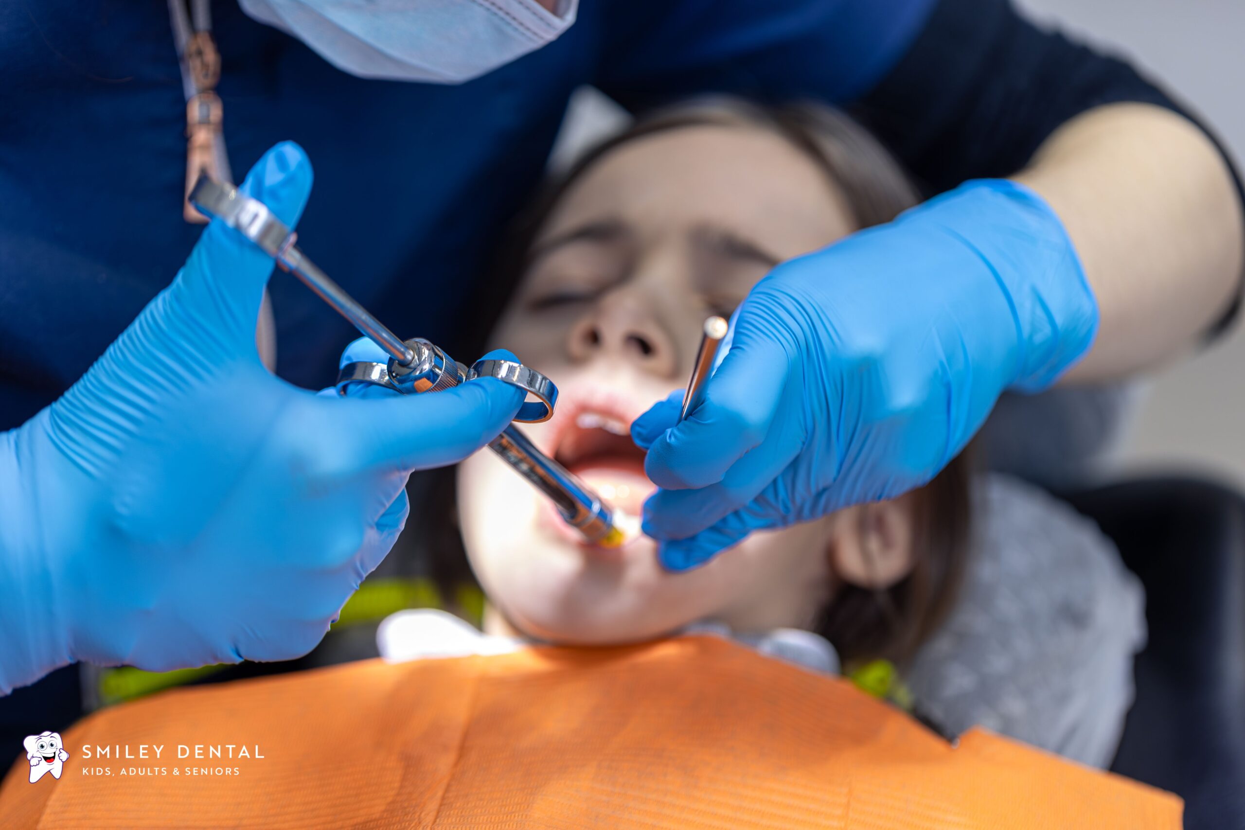 Dentist treating a young patient's tooth during an emergency dental visit at Smiley Dental