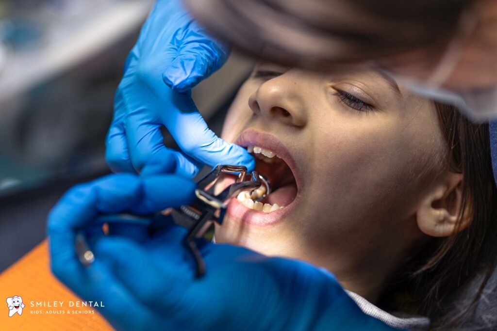 Dentist using dental instrument on patient's teeth during full mouth reconstruction procedure at Smiley Dental Boston