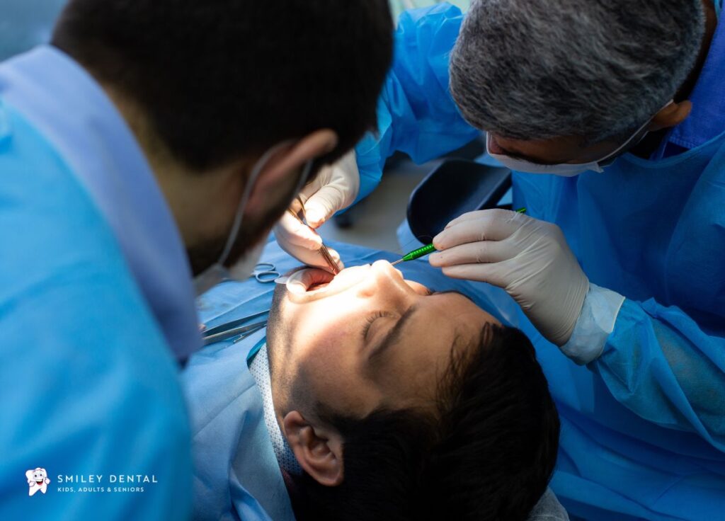 Dentist and dental assistant performing a surgical tooth extraction procedure on a patient at Smiley Dental