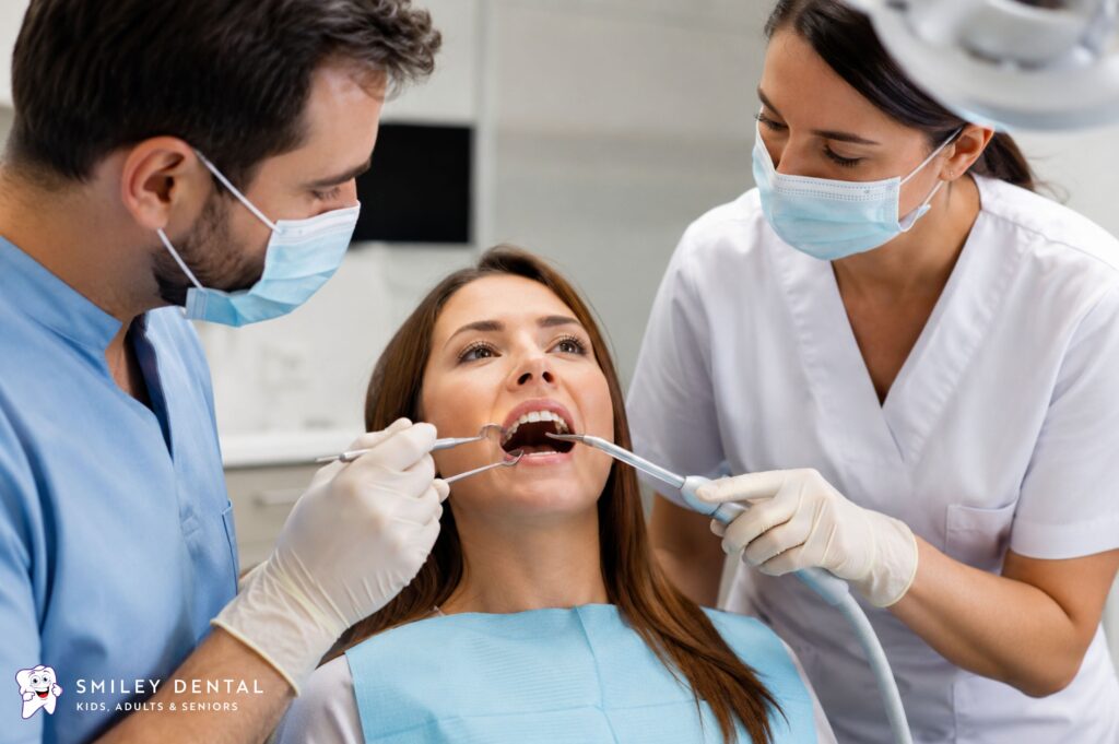 Dentist and assistant performing a dental cleaning procedure on a patient using scaling instruments