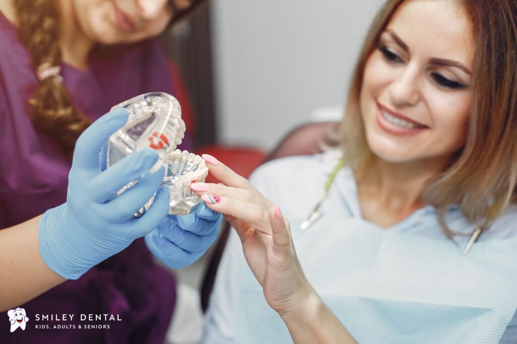 Dentist showing a patient a clear aligner model to compare Invisalign and traditional braces options in Boston