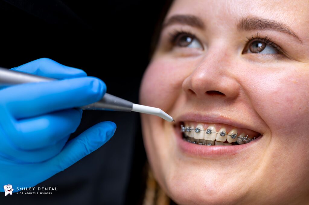 Dentist adjusting traditional metal braces on patient's teeth