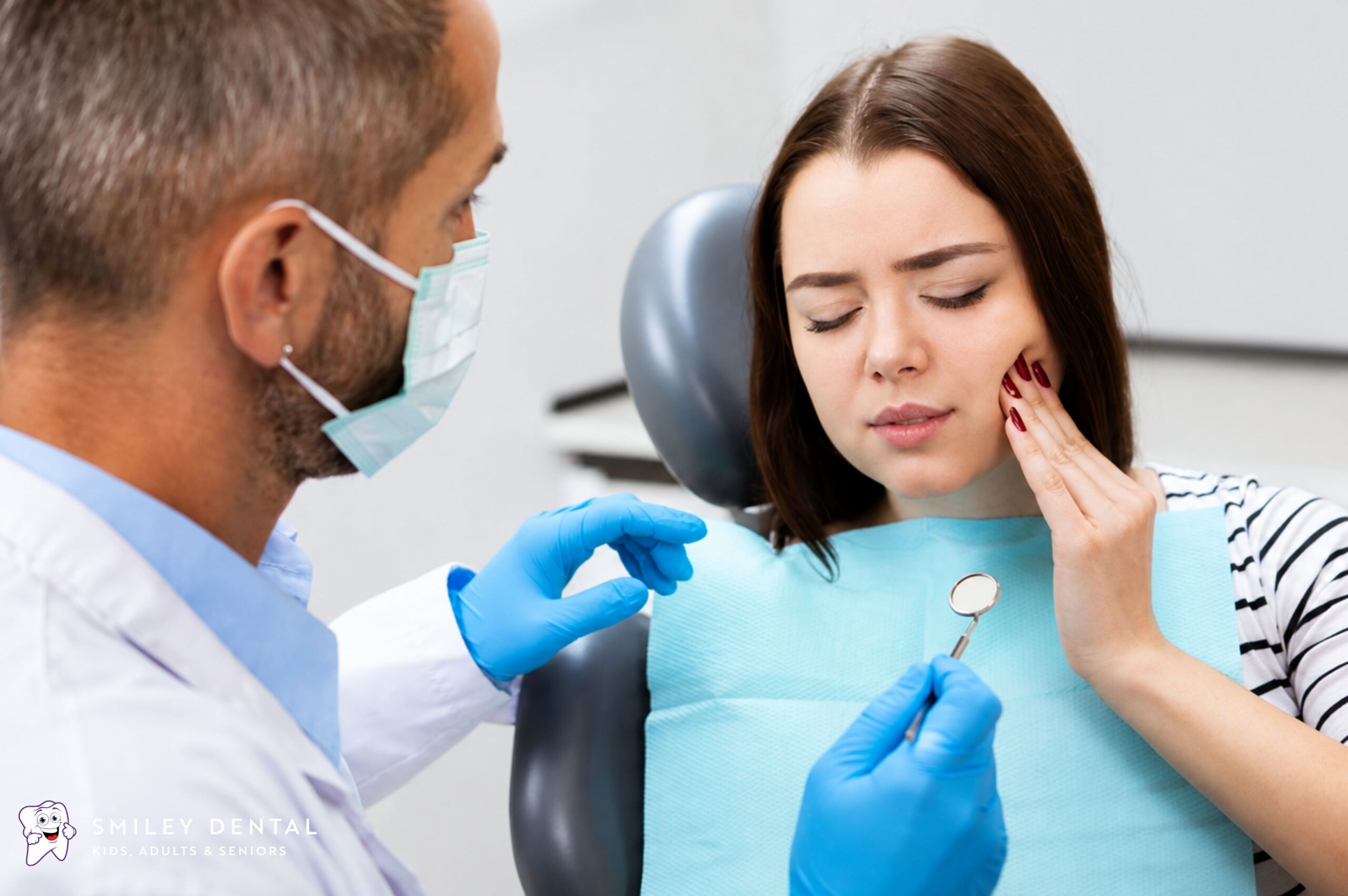 Woman holding her cheek in pain during a dental exam at Smiley Dental Boston before root canal treatment
