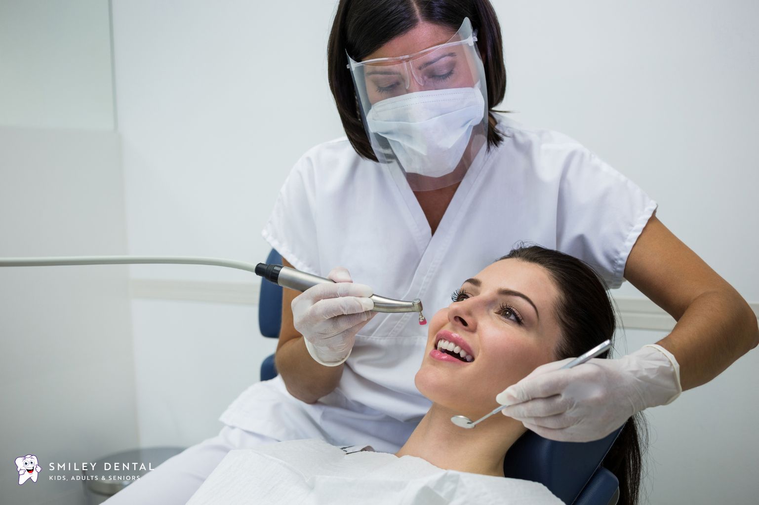 Dentist examining adult patient's teeth during full mouth reconstruction recovery visit